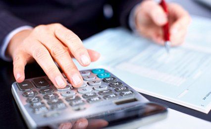 A man working on some figures using a calculator and pen