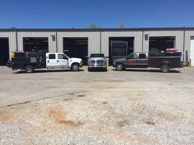 Three work trucks parked in front of a building on a sunny day.