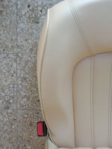porzione di sedile bianco appoggiato sul pavimento con cintura di sicurezza