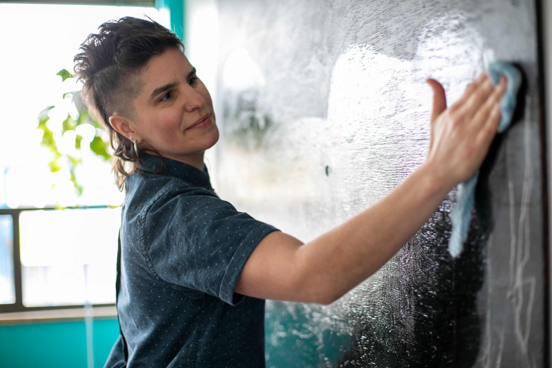 A person is cleaning a blackboard with a cloth.