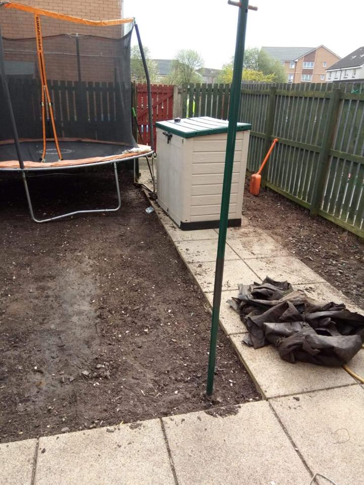 Backyard with trampoline, green storage box, fence, paving stones, and folded tarp on the ground