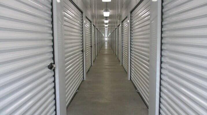 Long hallway of storage units with closed, ribbed metal doors.