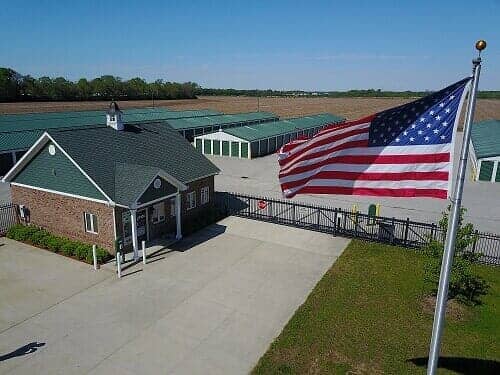 Storage facility with American flag waving; brick building and green roof.
