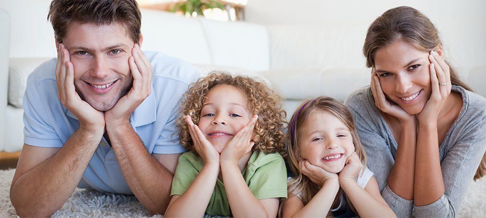 Young parents with two little girls, showing off white smiles