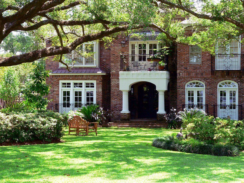 A large brick house with a lush green lawn in front of it