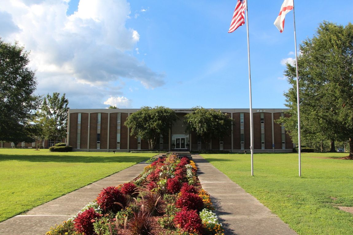 Two american flags are flying in front of a large building