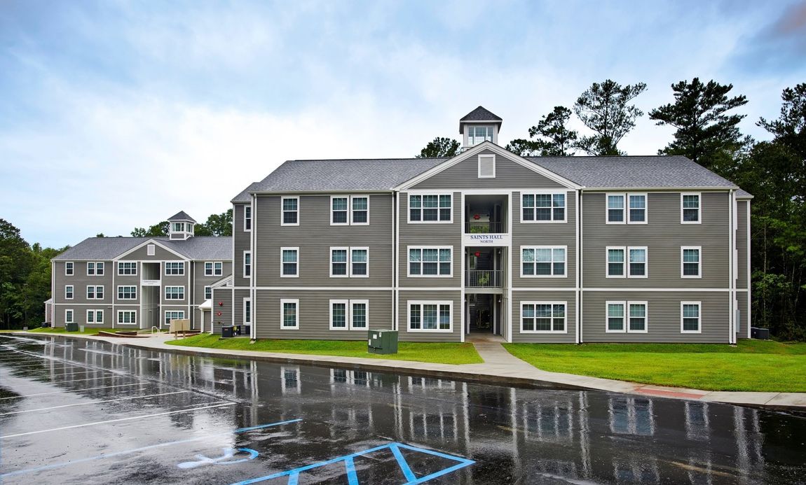 A large apartment building is reflected in a puddle of water