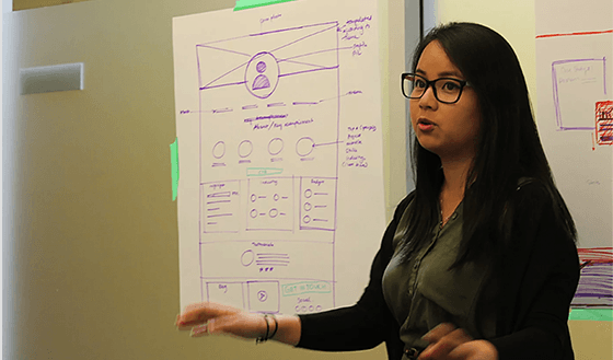 Una mujer está parada frente a una pizarra con un diagrama.
