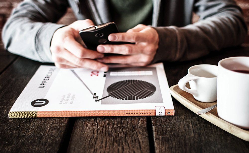 Un hombre está sentado en una mesa usando un teléfono celular.