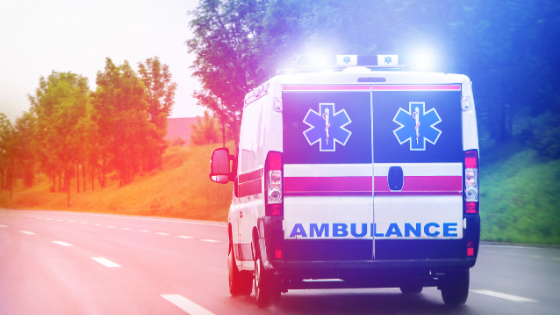 An ambulance is driving down a highway at night.