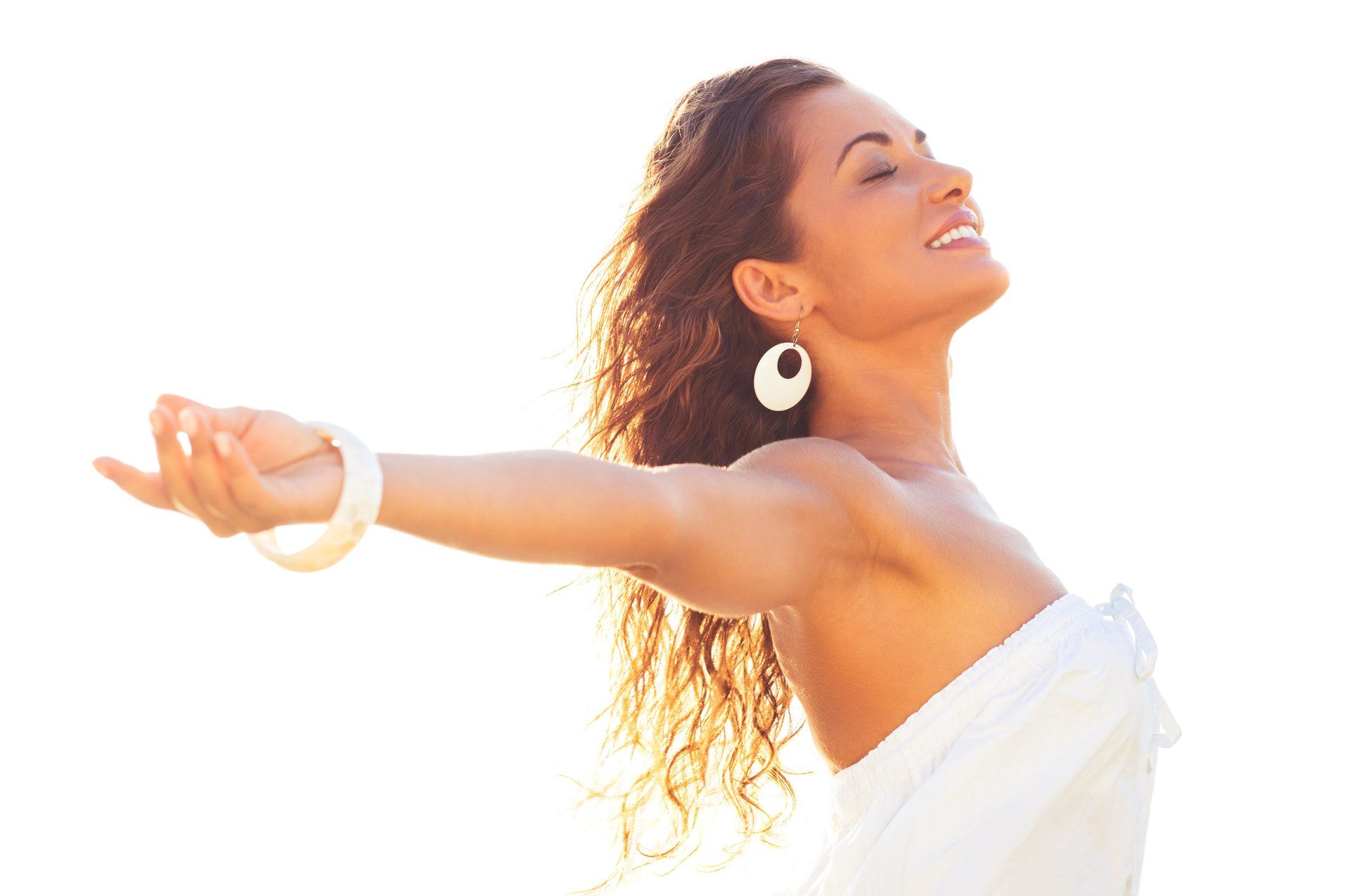 Woman with arms outstretched, eyes closed, smiling into bright sunlight.