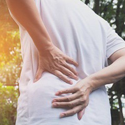 Lower Back Pain — Man Holding on His Lower Back In Cotuit, MA Lower Back Pain — Man Holding on His Lower Back In Cotuit, MA