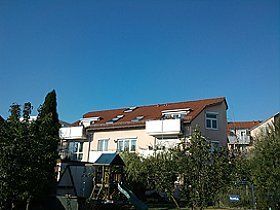 Ein großes Haus mit rotem Dach und einem Spielplatz davor.