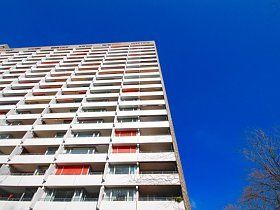 Ein hohes Gebäude mit vielen Balkonen vor einem blauen Himmel.