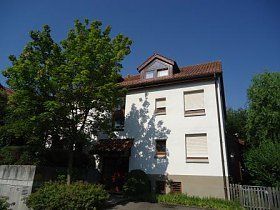 Ein großes weißes Haus mit einem Baum davor.