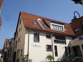 Ein weißes Gebäude mit einem roten Ziegeldach und Treppen auf dem Dach.