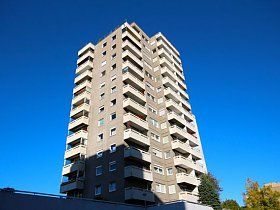 Ein hohes Gebäude mit vielen Balkonen vor einem blauen Himmel.