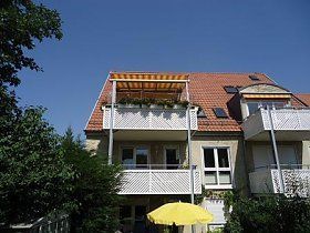 Ein Haus mit einem Balkon und einem gelben Sonnenschirm davor.