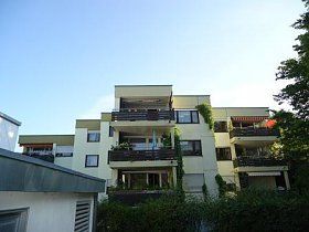 Ein großes Wohnhaus mit Balkonen und einem blauen Himmel im Hintergrund.