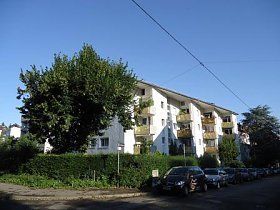 Ein Gebäude, vor dem viele Autos geparkt sind.