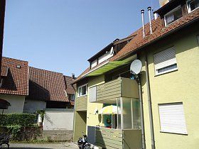 Ein gelbes Gebäude mit einem Balkon und einer Satellitenschüssel an der Seite.