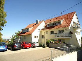 Ein weißes Gebäude mit einem roten Dach und davor geparkten Autos