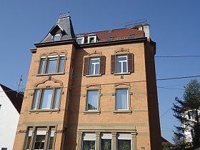 Ein großes Backsteingebäude mit rotem Dach und vielen Fenstern.