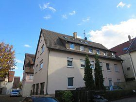 Ein großes weißes Gebäude mit einem davor geparkten Auto.