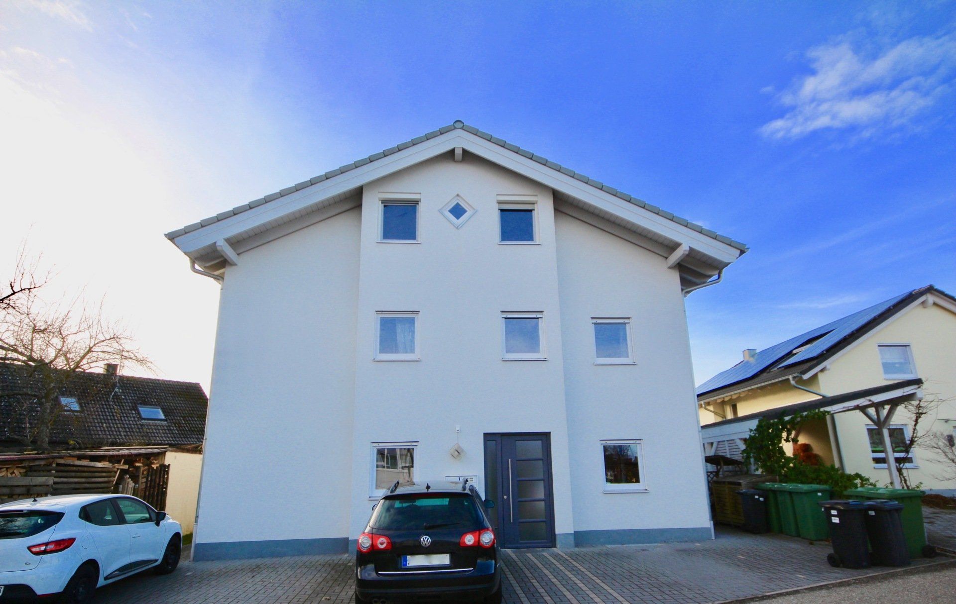 Ein weißes Haus mit einem davor geparkten Auto.