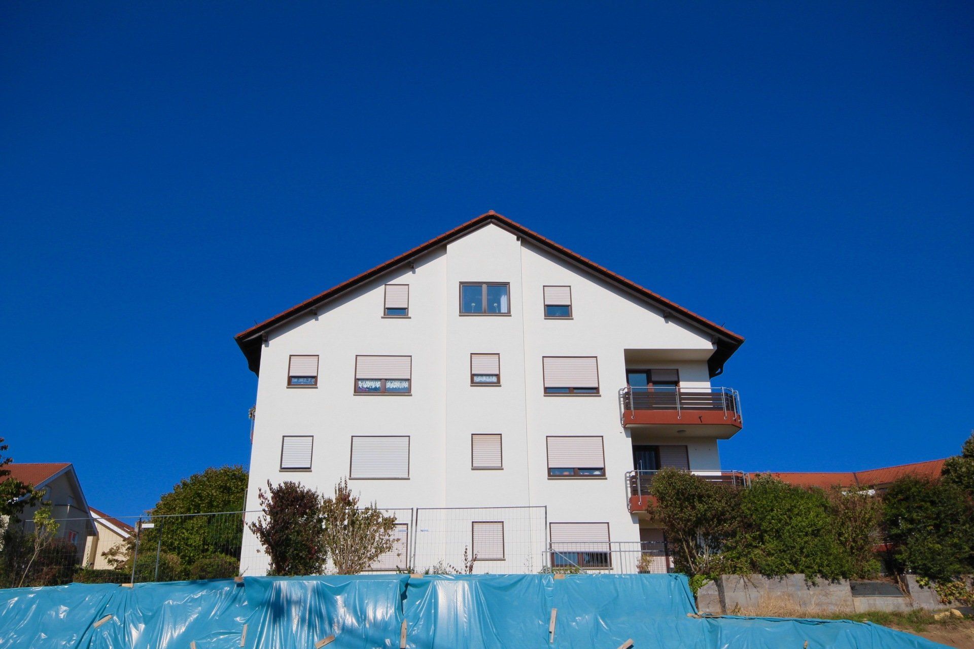 Ein großes weißes Gebäude mit einer blauen Wand davor