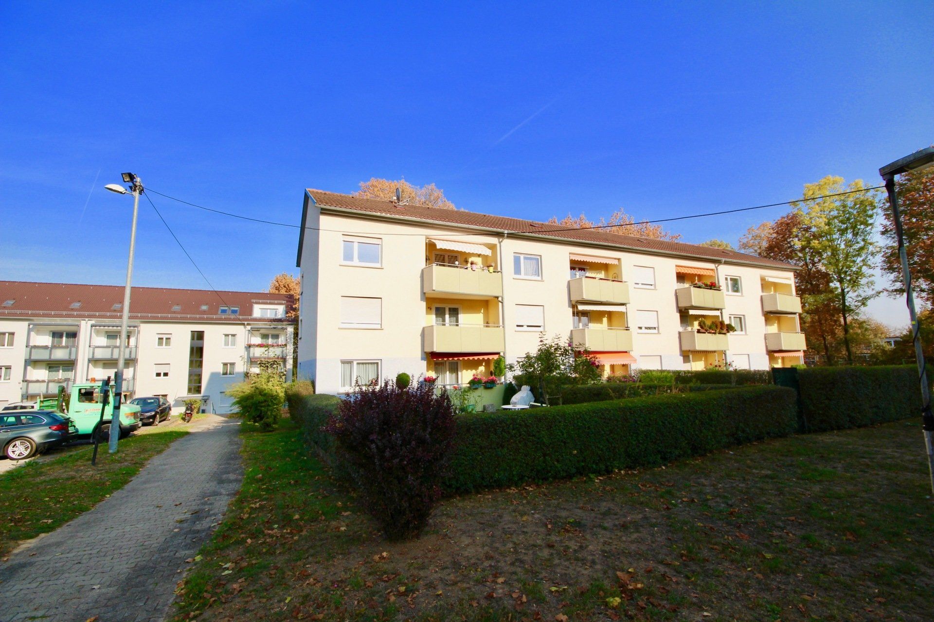 Ein großes Mehrfamilienhaus mit vielen Balkonen und einem davor geparkten grünen Lastwagen.