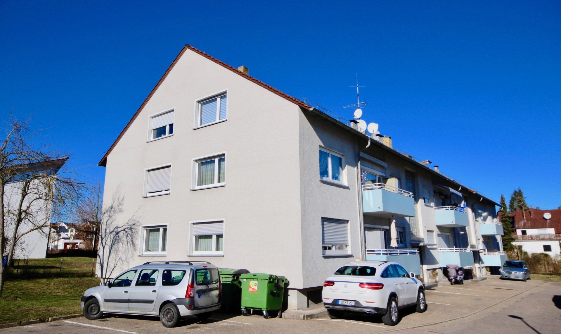 Ein weißes Gebäude mit davor geparkten Autos.
