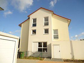 Ein weißes Haus mit rotem Dach steht neben einer Garage.
