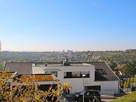 Ein großes weißes Haus mit einem davor geparkten Auto und Blick auf eine Stadt.