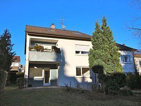 Ein großes weißes Haus mit einem Balkon und einer Satellitenschüssel auf dem Dach.