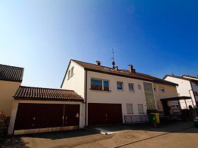 Ein weißes Haus mit einer Garage und einem blauen Himmel im Hintergrund.