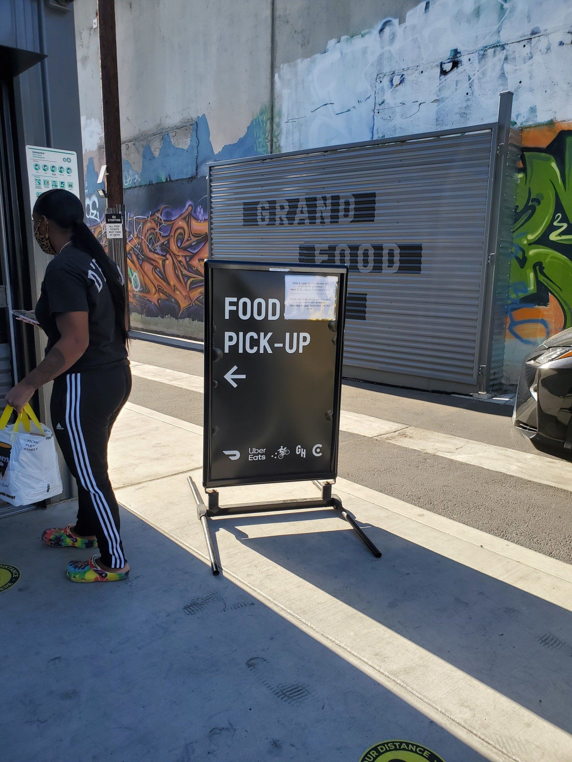 Person picking up food from a shop. Sign reads 
