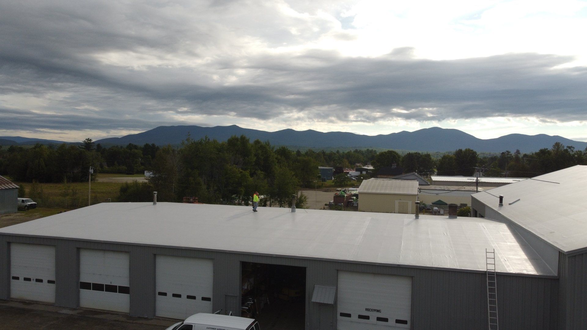 Rodd Roofing’s metal retrofit project on an industrial building, set against mountains and cloudy skies.