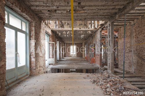 Innenansicht eines im Bau befindlichen Gebäudes; Ziegelwände und Schutt, Fenster, freiliegende Deckenbalken.