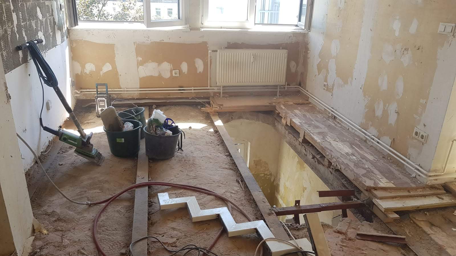 Raum im Umbau mit freiliegenden Dielen, Gipswänden und Werkzeugen; Innenansicht.