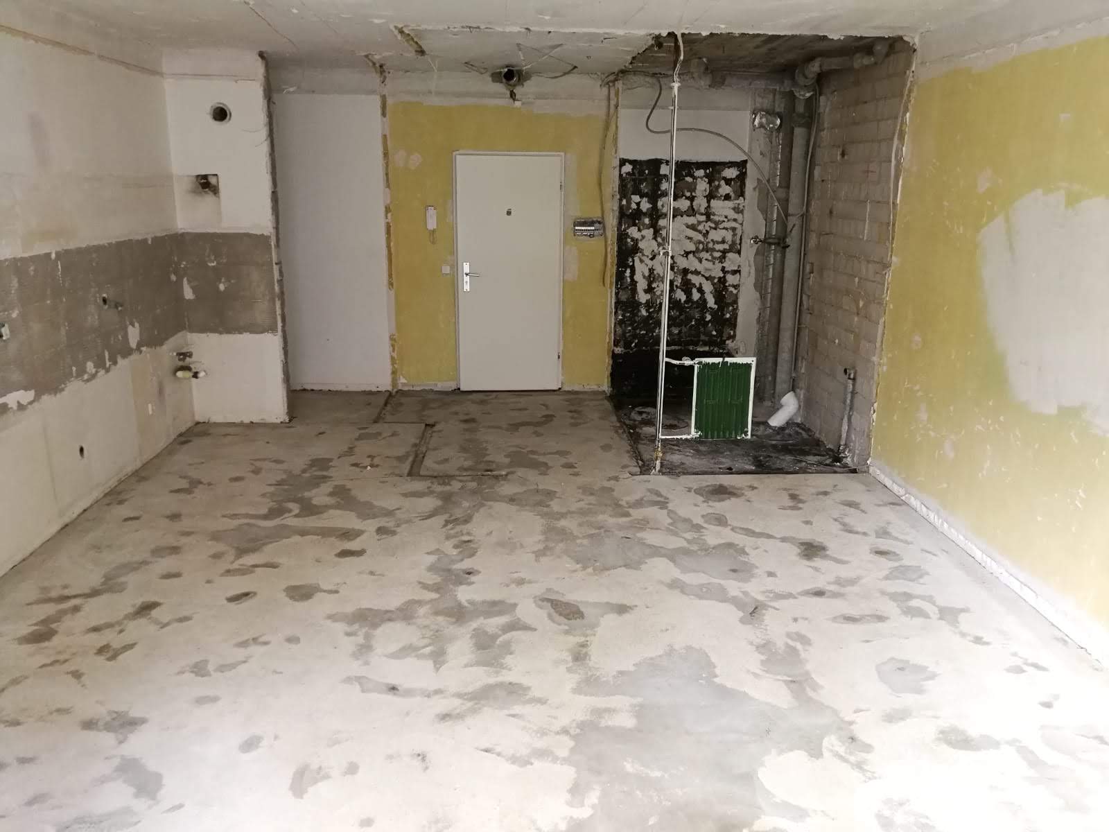 Innenraum wird renoviert, mit freiliegenden Wänden, Tür und Betonboden.