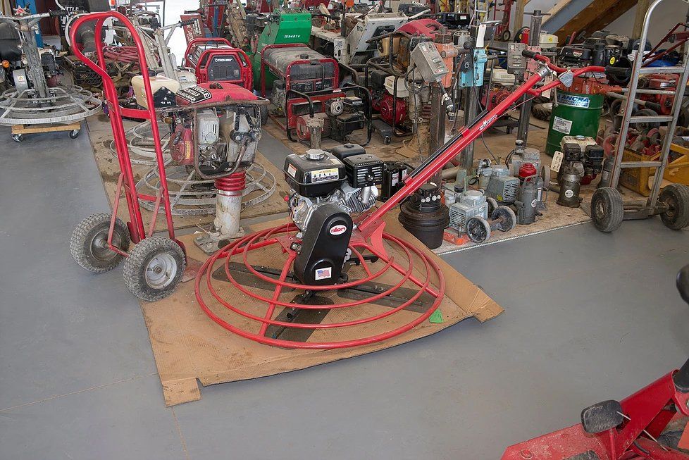 Red concrete finishing machine and other construction equipment in a workshop.
