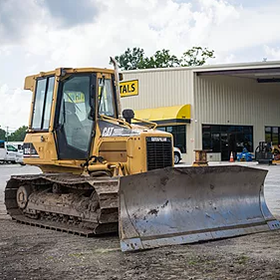 Yellow Caterpillar bulldozer parked in front of a building with a 