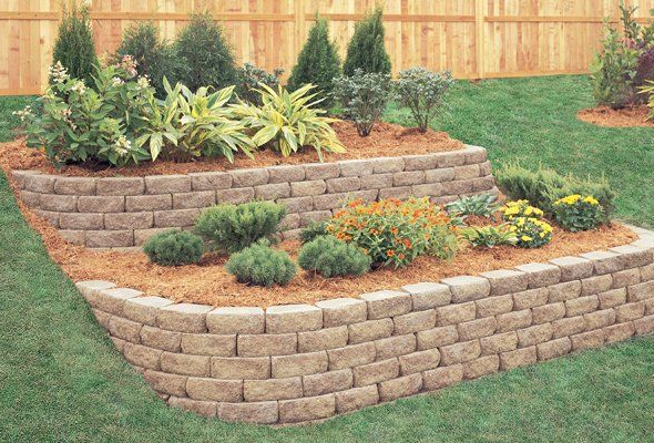 A brick wall with flowers and shrubs in it