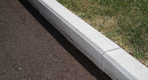 A concrete curb is sitting on the side of a road next to a grassy area.