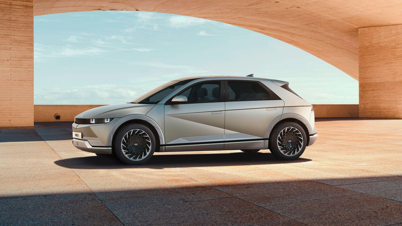 A silver electric car is parked in front of a building.  ioniq 5 