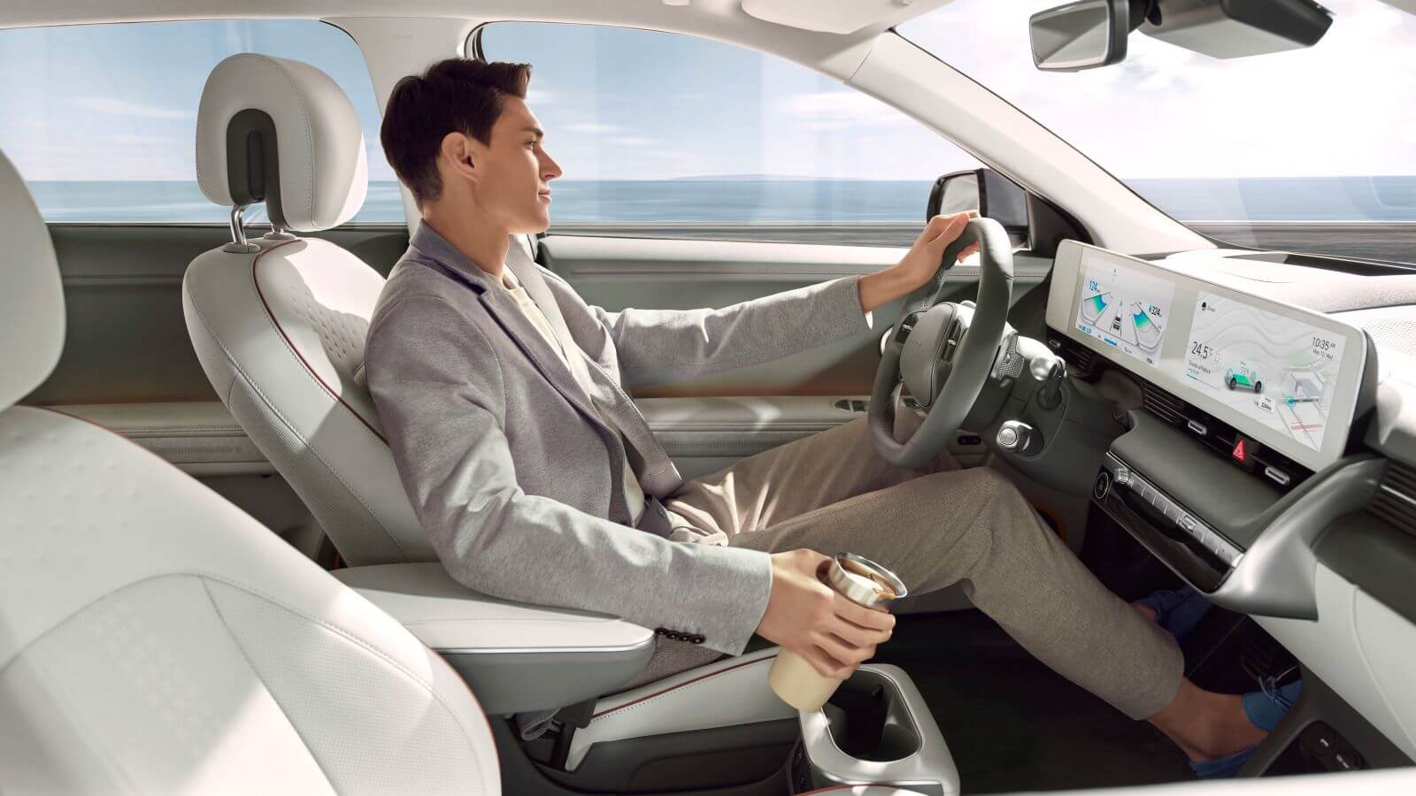 A man is sitting in the driver 's seat of a car holding a cup of coffee.