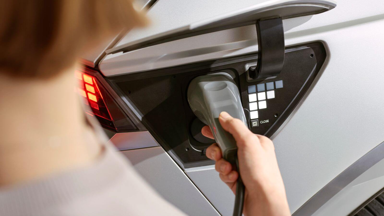 A woman is charging her electric car with a charger.