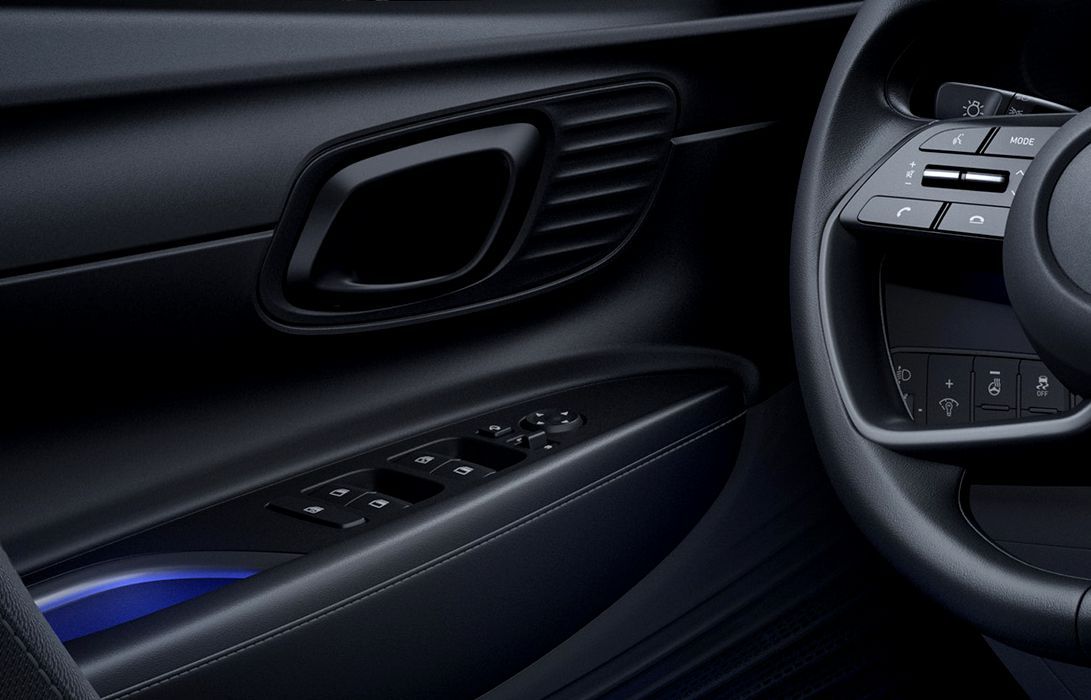 A close up of a car door with a steering wheel and controls. i20