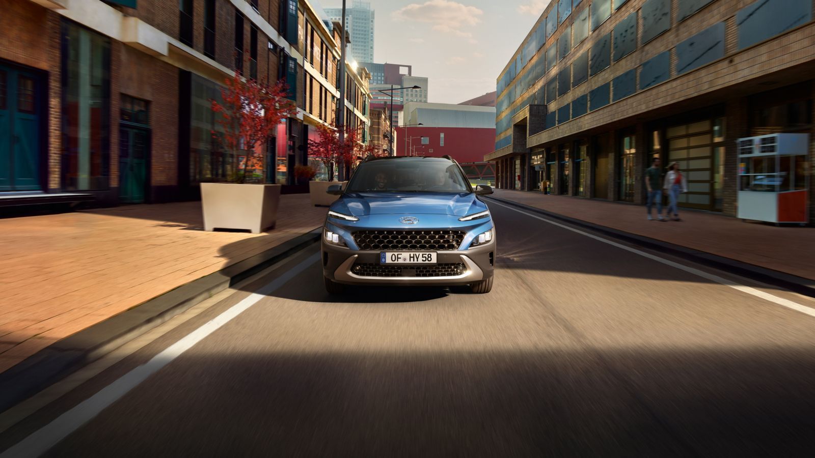 A blue car is driving down a city street.